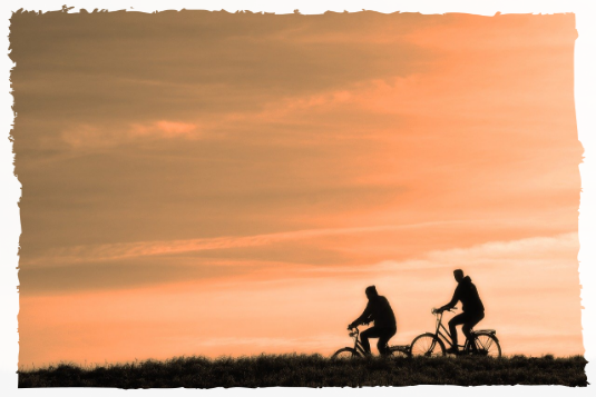 Two people cycling at sunset